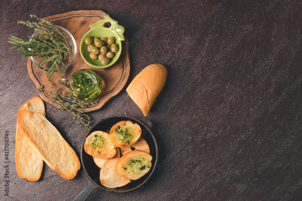 Tasty bread with different herbs on dark background