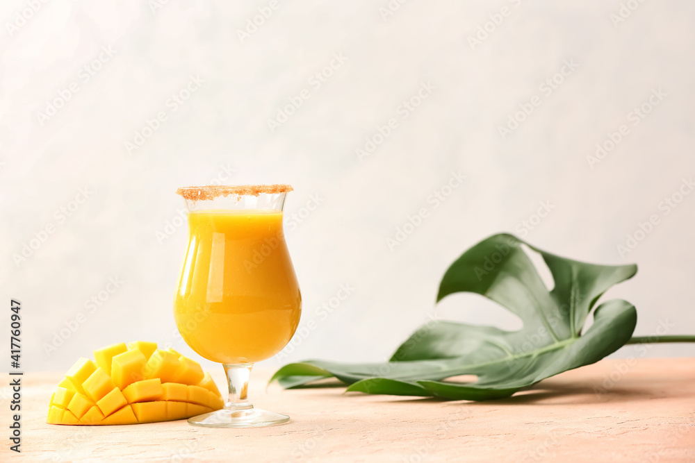 Glass of tasty mango smoothie on color background