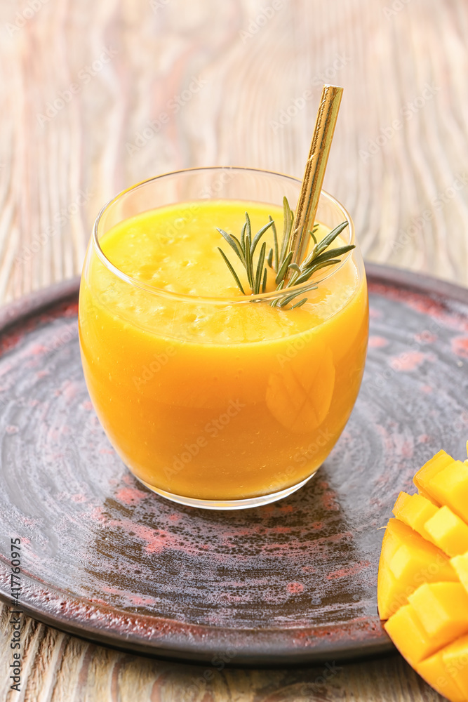 Glass of tasty mango smoothie on wooden background