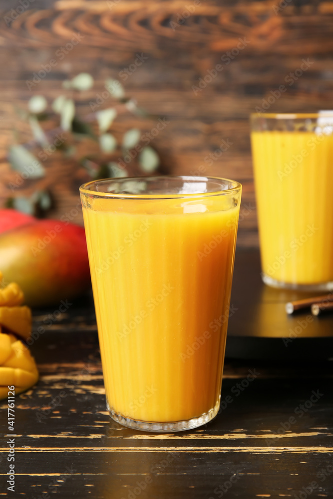 Glasses of tasty mango smoothie on dark wooden background