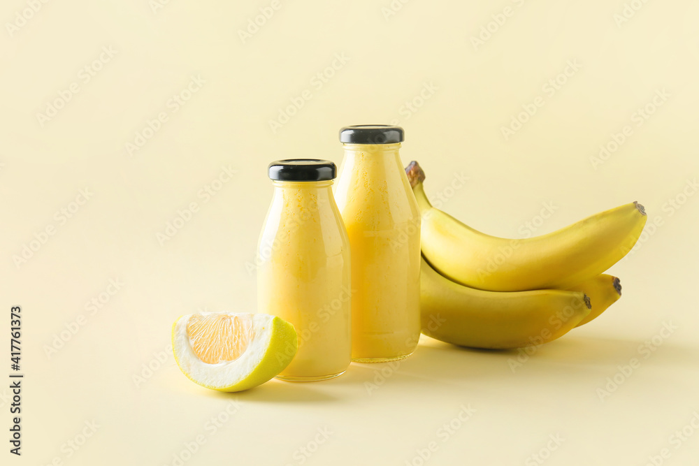 Bottles of tasty banana smoothie on color background