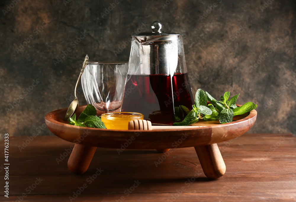 Teapot of hot hibiscus tea with honey and mint on tray