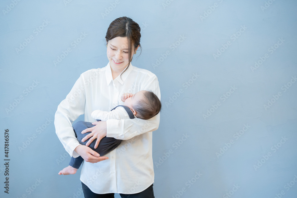 寝ている赤ちゃんを抱っこするお母さん