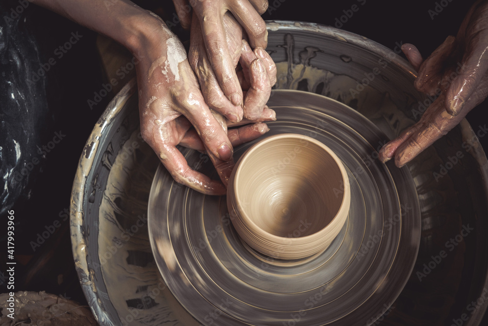 Hands of the master potter and vase of clay on the potters wheel