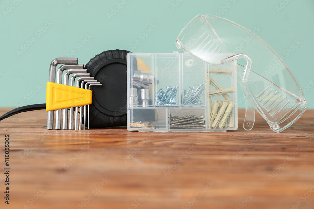 Set of construction tools on wooden table against color background, closeup