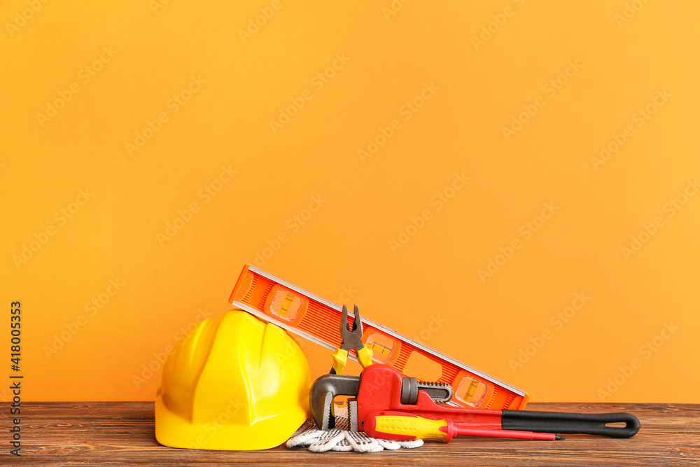 Set of construction tools on wooden table against color background