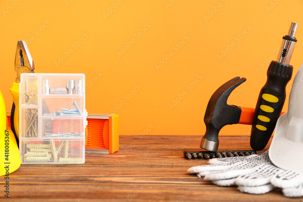 Set of construction tools on wooden table against color background