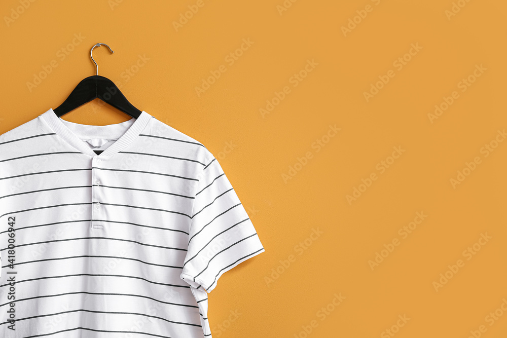 Hanger with t-shirt on color background