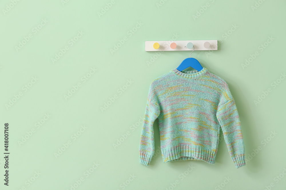 Hanger with sweater on color background