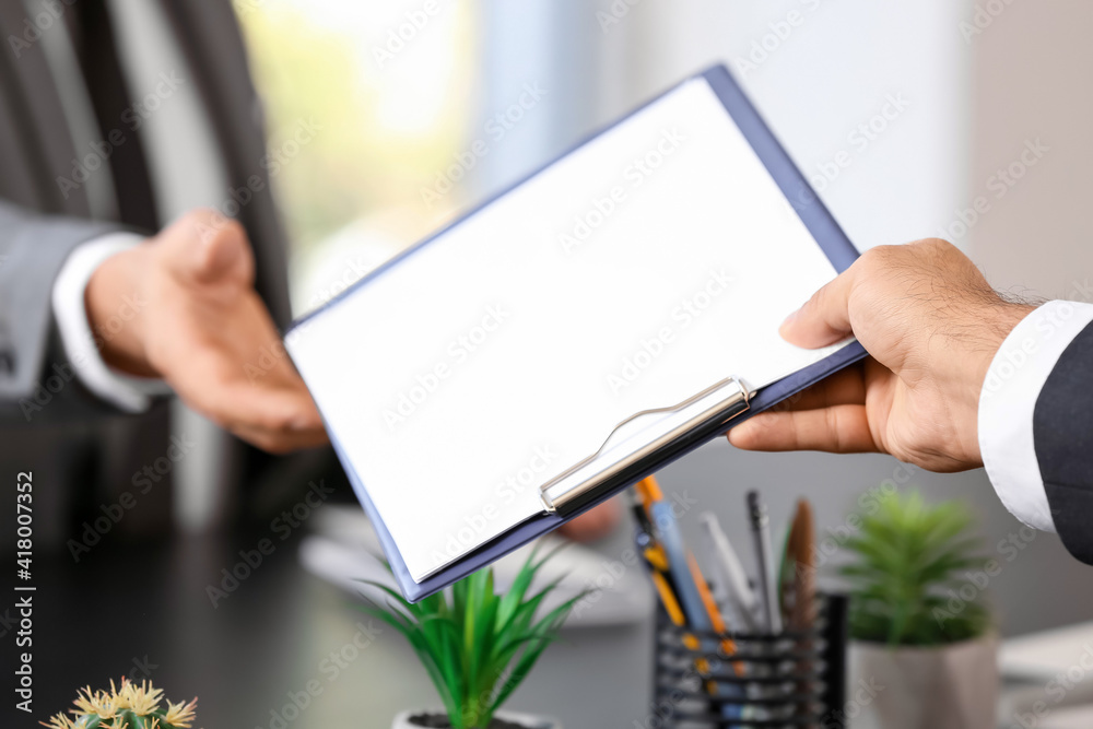 Young businessmen with clipboard in office