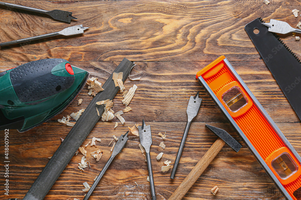 Set of carpenters tools and saw dust on wooden background