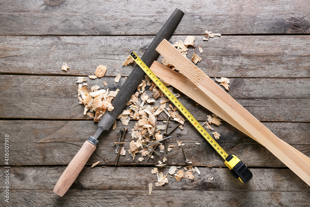 Carpenters file, measure tape and bars on wooden background