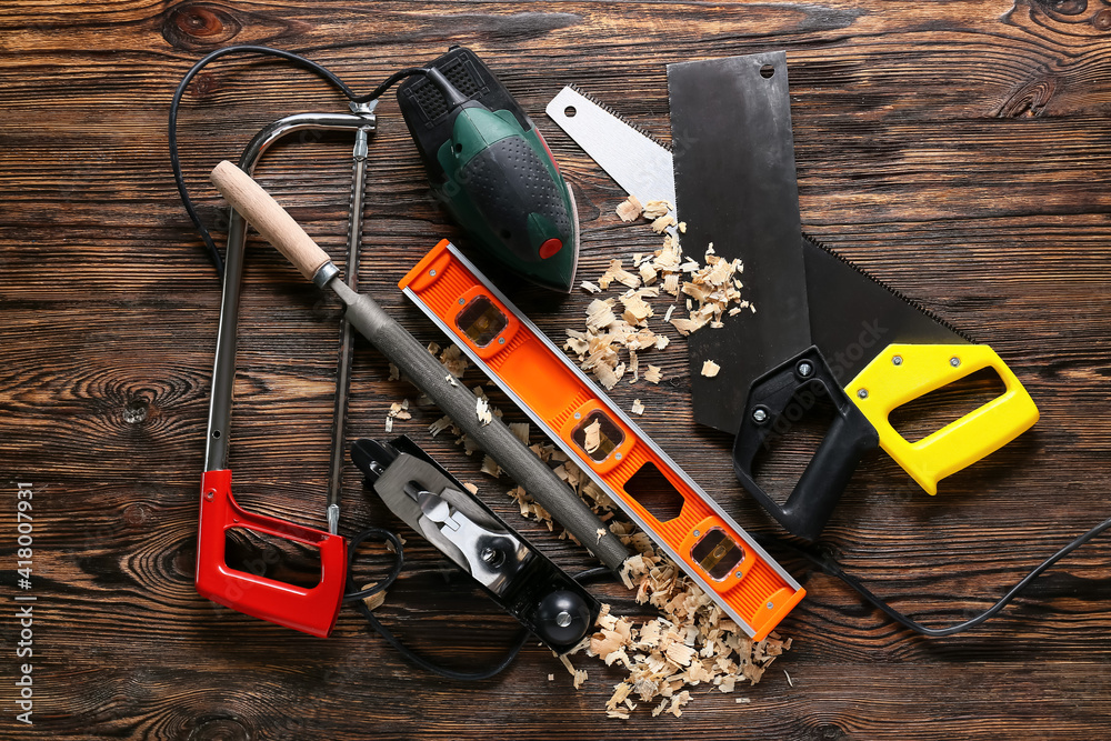 Set of carpenters tools and saw dust on wooden background