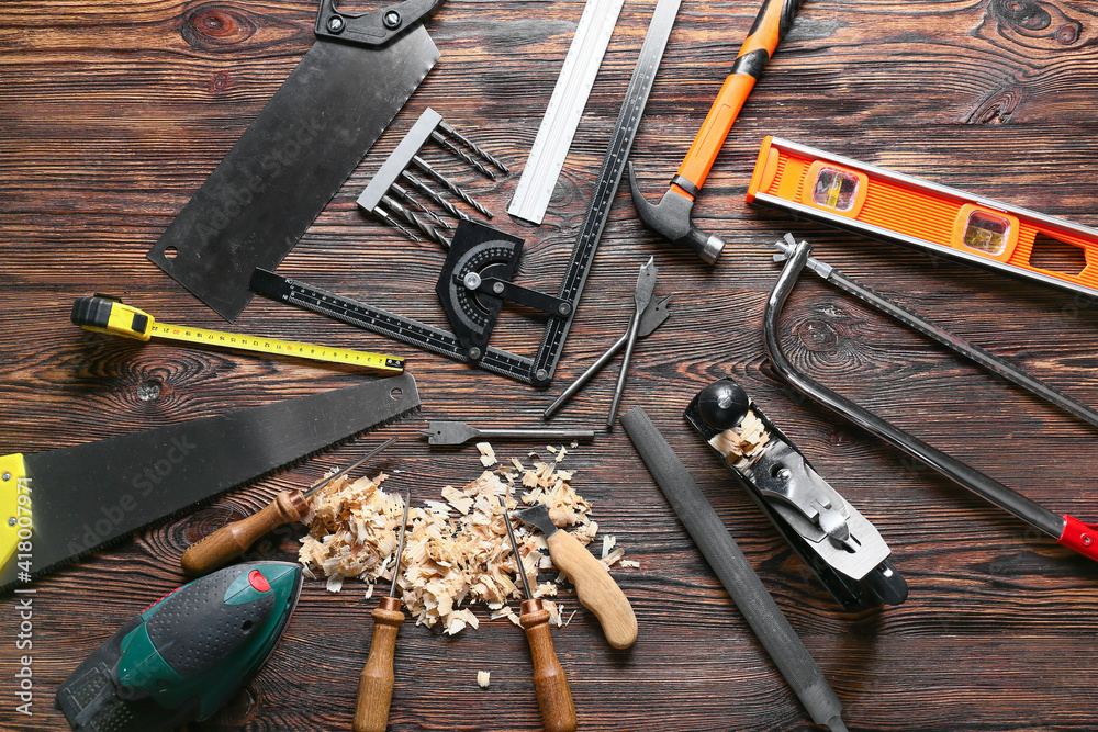 Set of carpenters tools and saw dust on wooden background