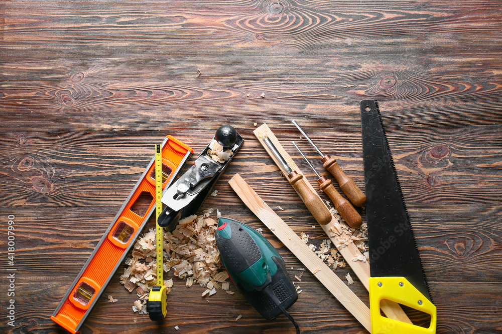 Set of carpenters tools and saw dust on wooden background