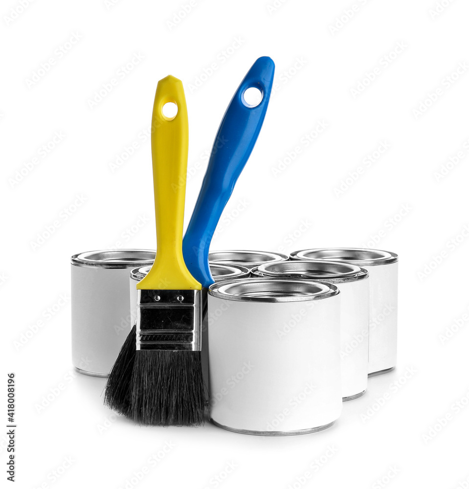 Cans of paint and brushes on white background