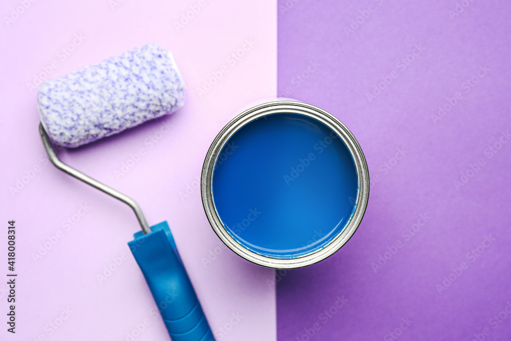 Can of blue paint and roller on color background