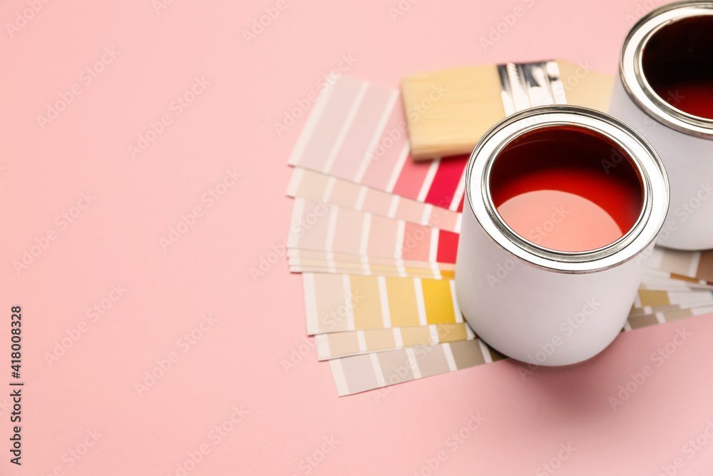 Cans of paints with palette samples and brush on color background