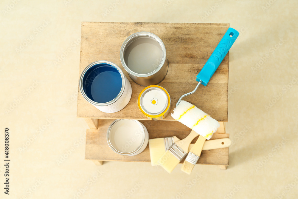 Cans of paints and tools on step ladder in room