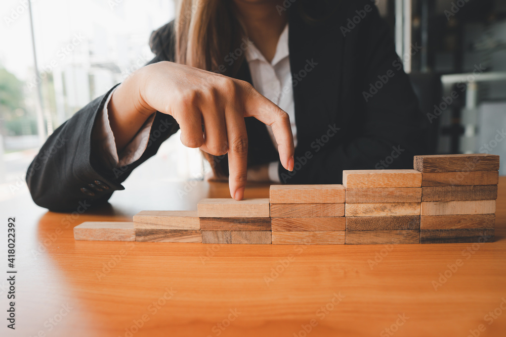 Persons hand walking up a set of wooden blocks. Business development and growth concept