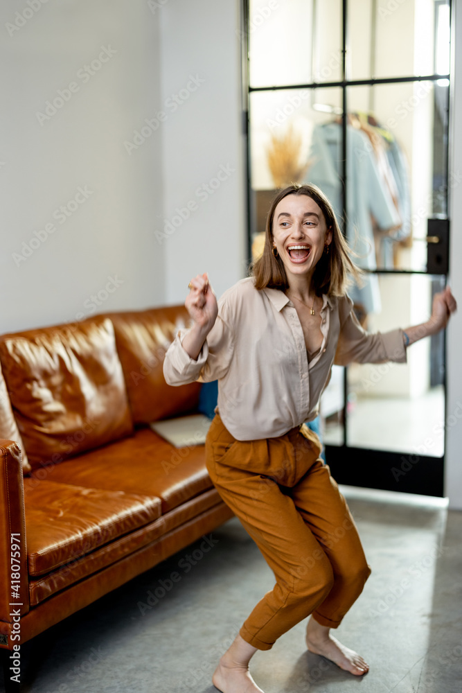 Happy woman jumps from the brown sofa to the floor at living room. Jump for joy and good news