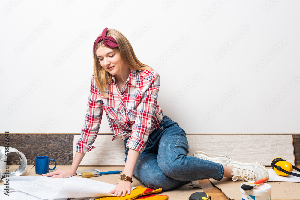 Happy girl sitting on floor with blueprint