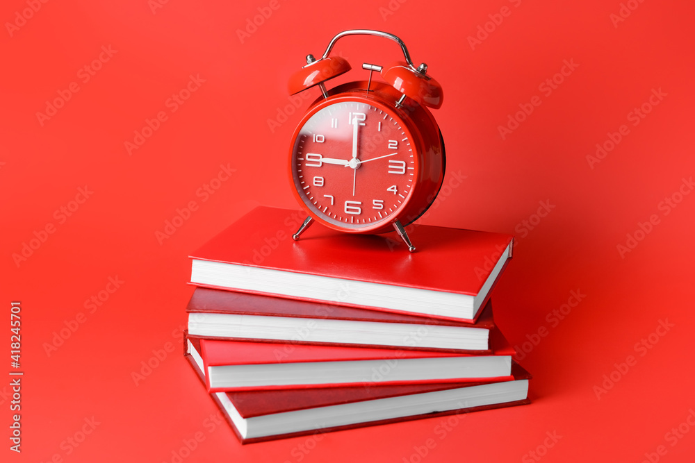 Alarm clock and blank books on color background