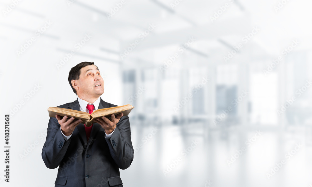 Smiling businessman with open book looking up