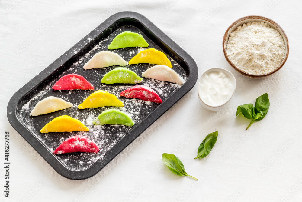 Top view of colorful raw dumplings on baking sheet