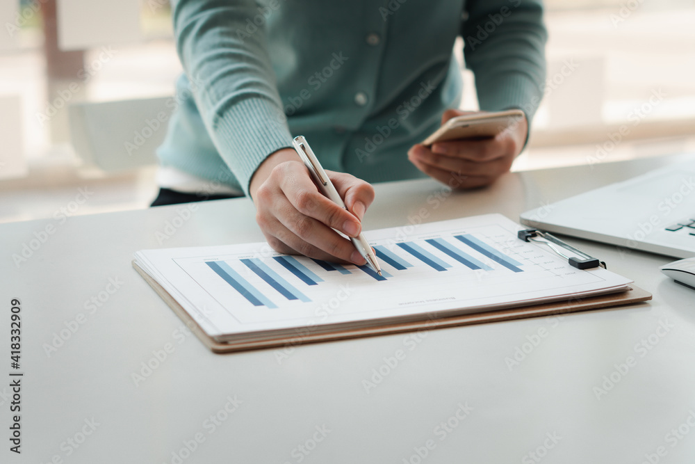 Businessmen are analyzing business graphs on their desks and calculating them using a calculator. Fi