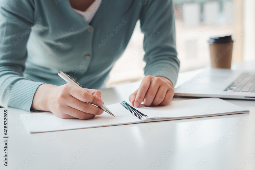 Business women work on computers and write on notepad with pen to calculate financial statements wit