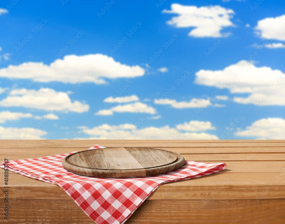 Wooden cutting board and tablecloth on wooden table