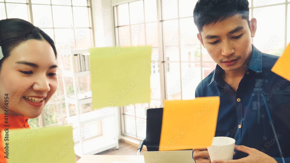 Business people work on project planning board in office and having conversation with coworker frien