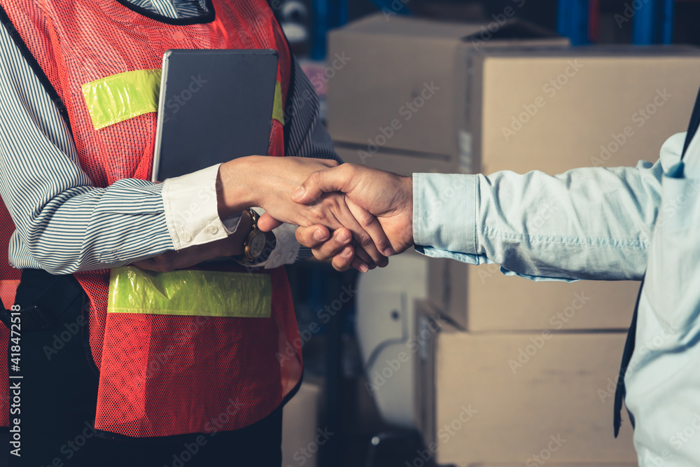 Warehouse worker handshake with manager in storehouse . Logistics , supply chain and warehouse busin