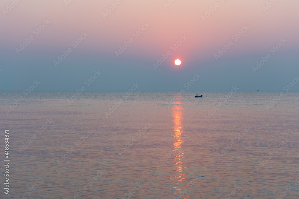 海滩上令人惊叹的日落。太阳从海上升起。柔和的色调