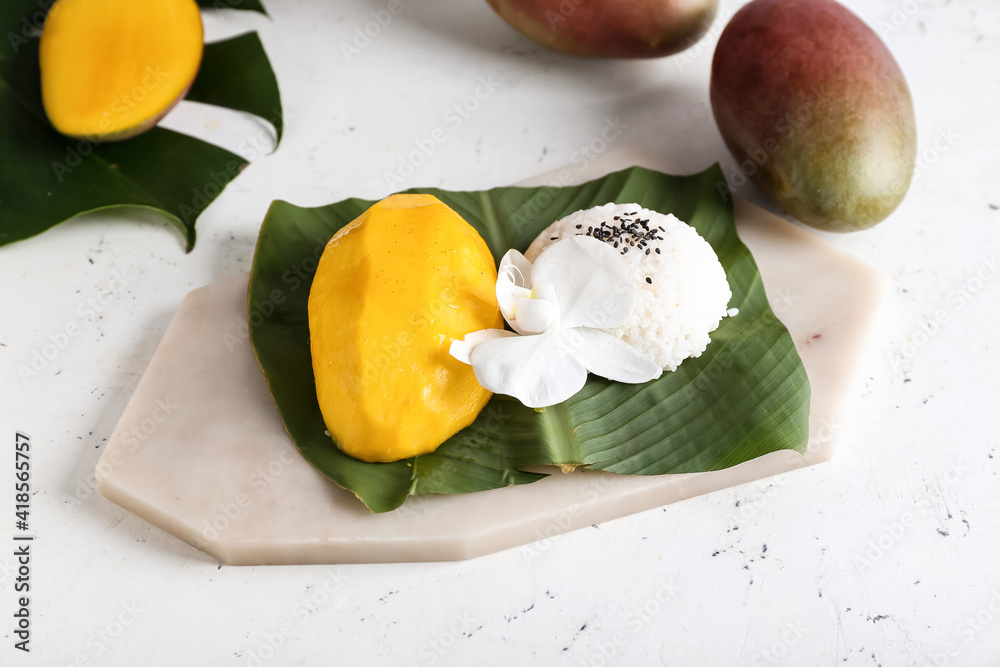 Tropical leaf with tasty rice and mango on light background