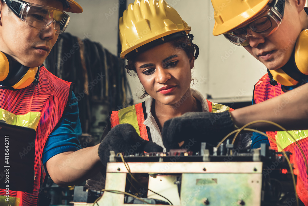 Group of skillful workers using machine equipment in factory workshop . Industry and engineering peo