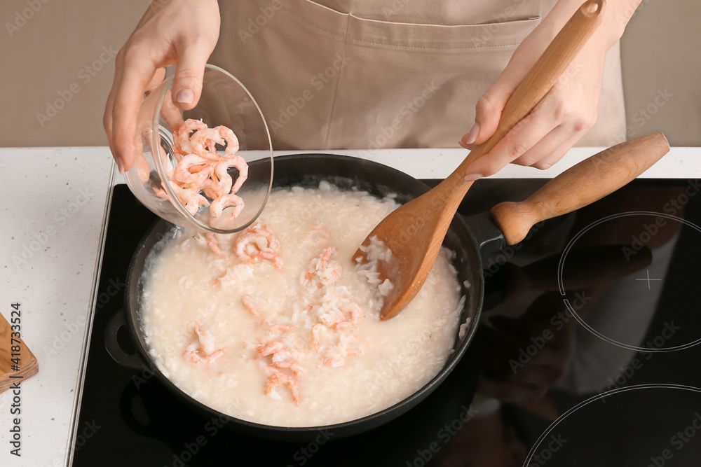 Woman cooking risotto in kitchen