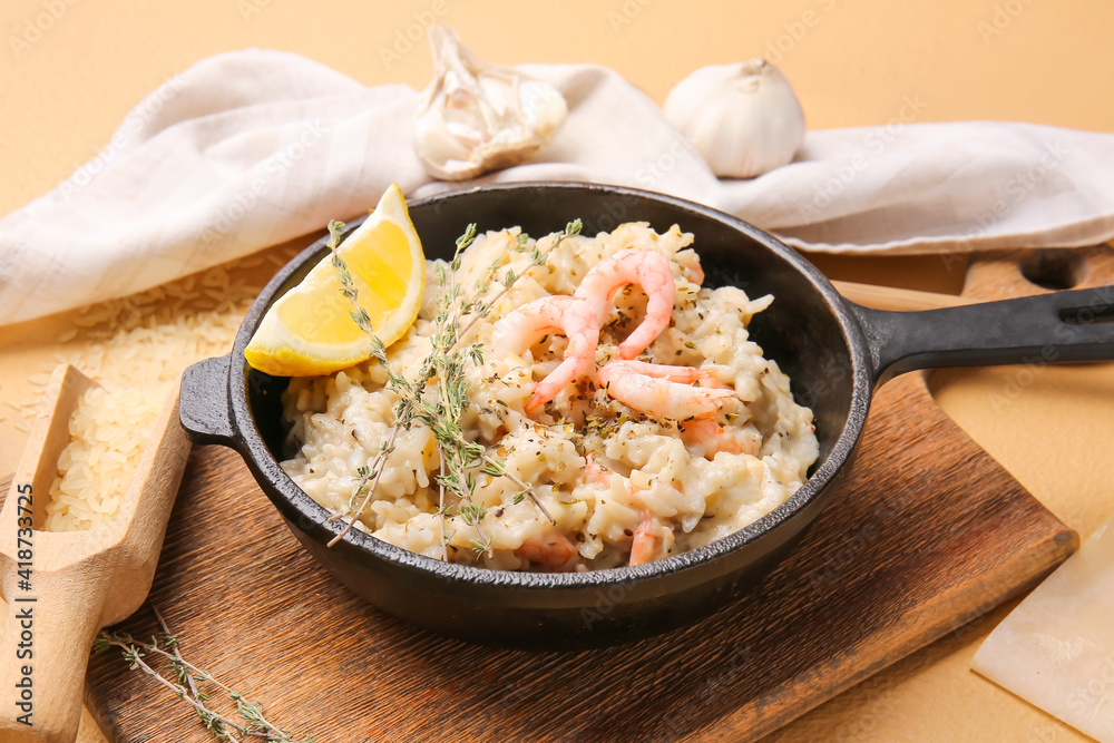 Frying pan with tasty risotto on color background