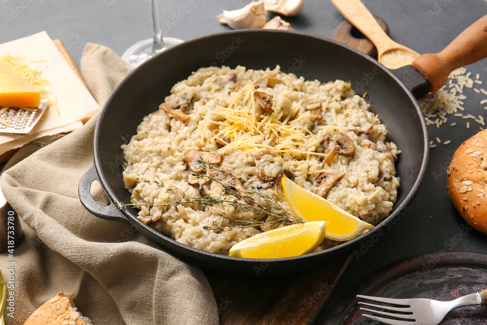 Frying pan with tasty risotto on dark background