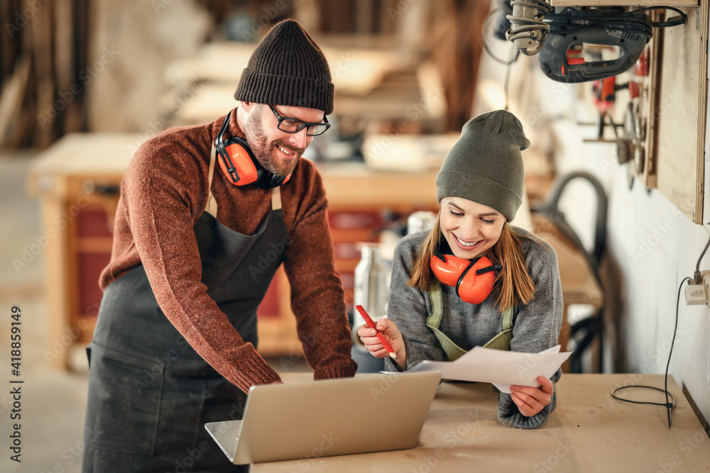 Cheerful joinery owners discussing project on laptop