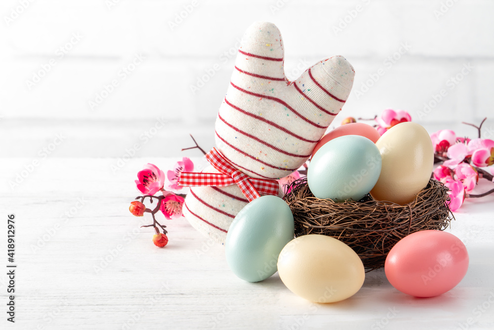 Close up of colorful Easter eggs in the nest with pink plum flower.