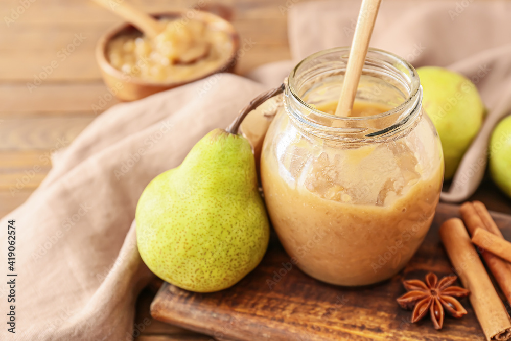 Jar of tasty pear jam on wooden table