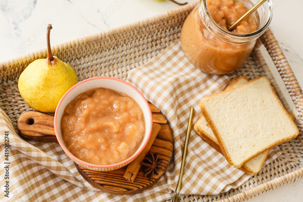 Tray with tasty pear jam and bread on table