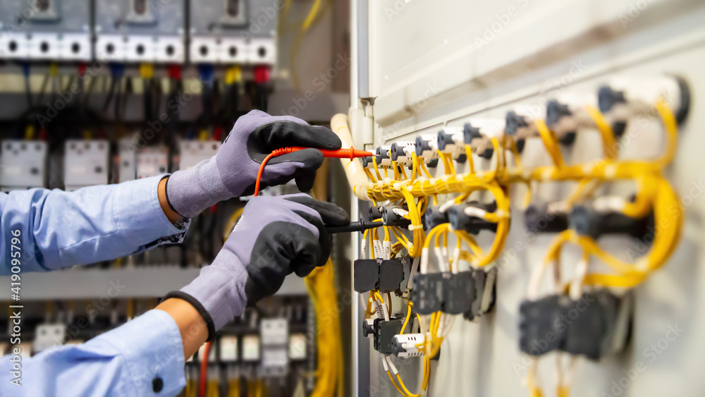 Electrical engineer using digital multi-meter measuring equipment to checking electric current volta