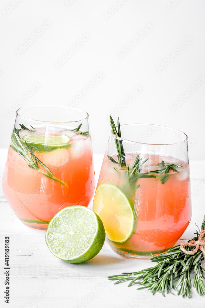 sliced lime, rosemary and natural juice in glass on white table background