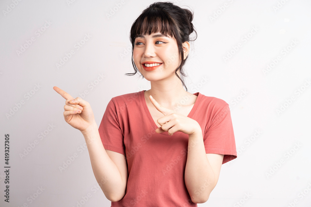 Young Asian woman posing on white background, using finger to pointing and showing, hand gesture