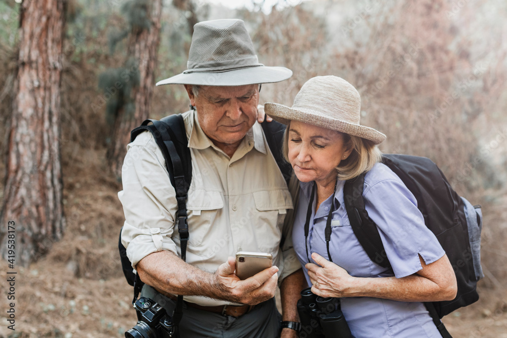 Senior partners using their smartphone in the forest