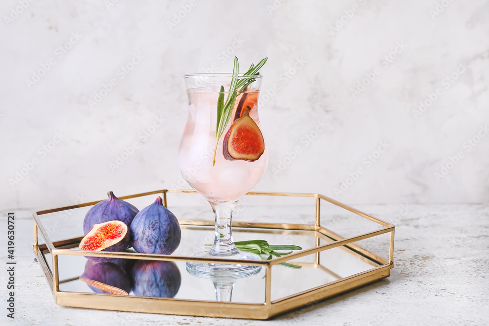 Tray with glass of tasty fig lemonade on light background