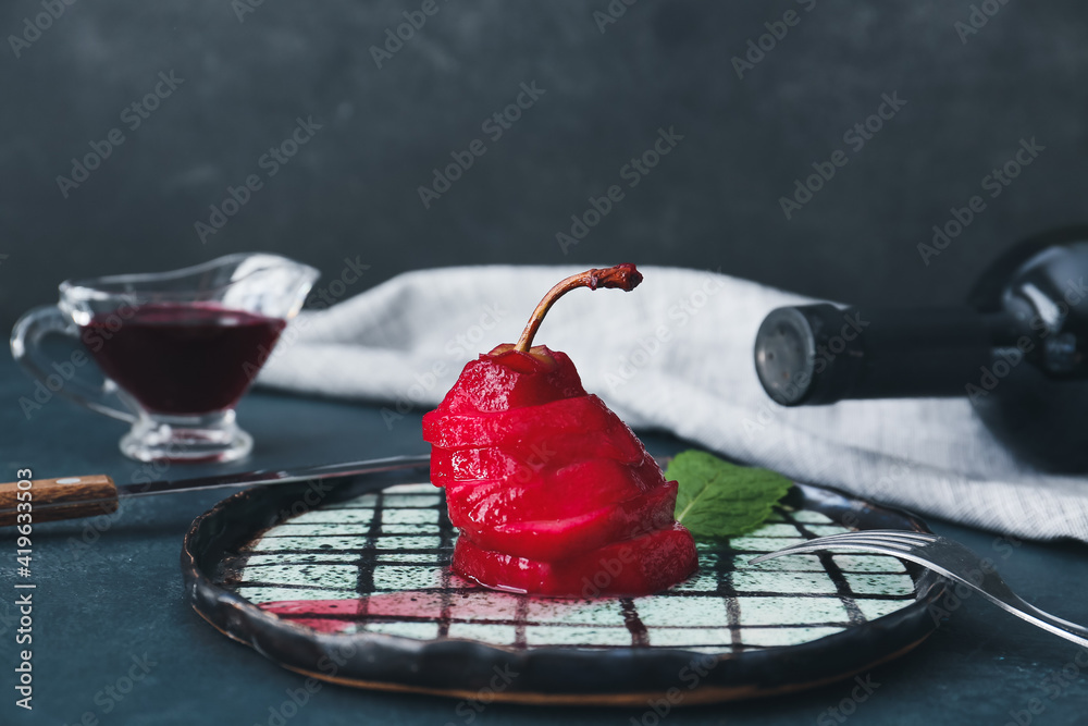 Plate of tasty poached pears in wine sauce on dark background